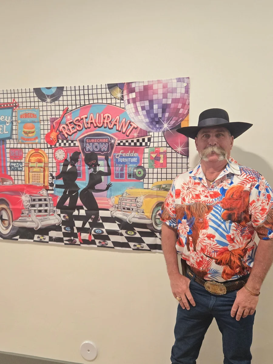 Kevin wearing a colorful shirt beside artwork