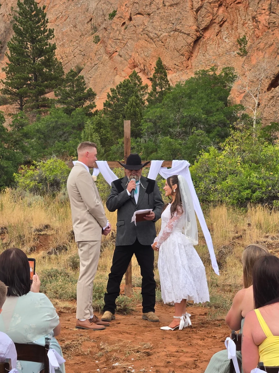 Kevin with a wedding couple at an outdoor ceremony with red rock cliffs behind them